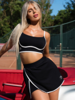 Souprava z černé sportovní sukně s hlubokým rozparkem a bílým lemováním a podprsenky s nastavitelnými ramínky.