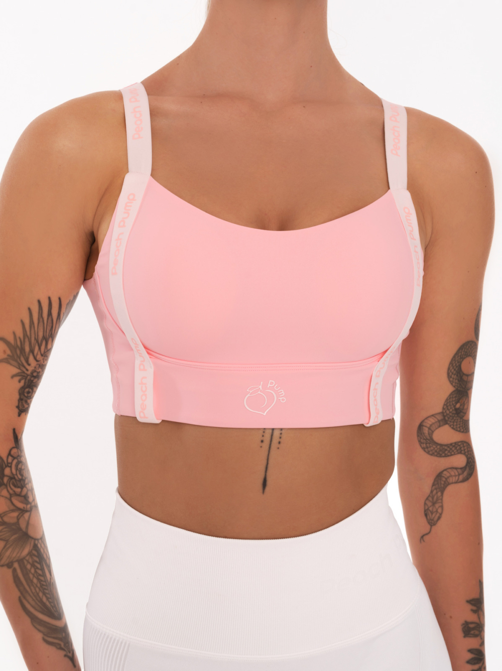 Pink sports bra with white straps and pink Peach Pump lettering