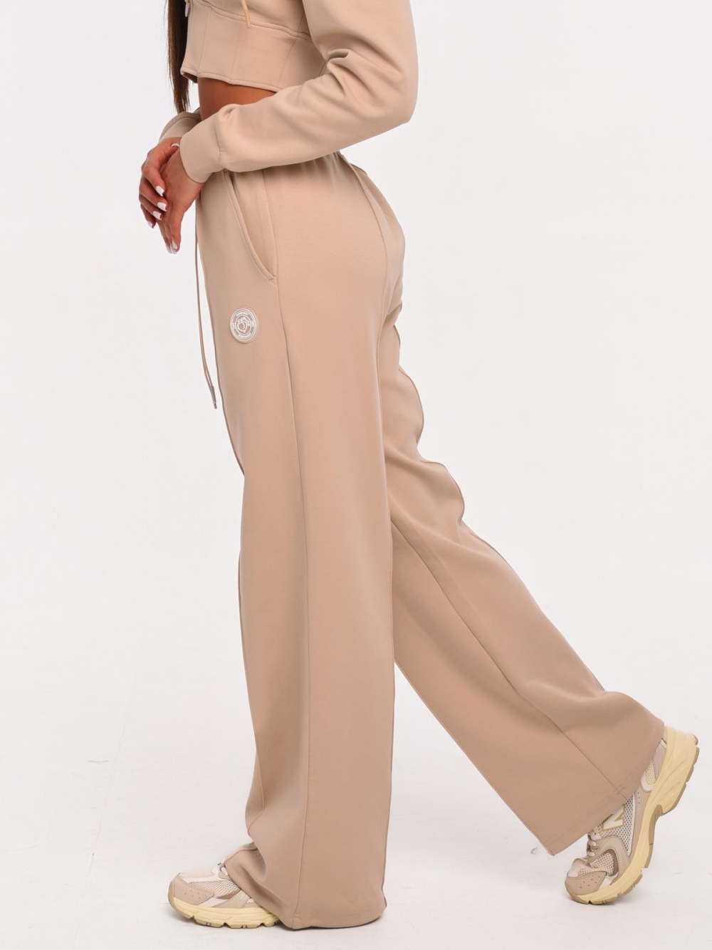 Women's beige joggers with vertical seams that visually elongate the silhouette.