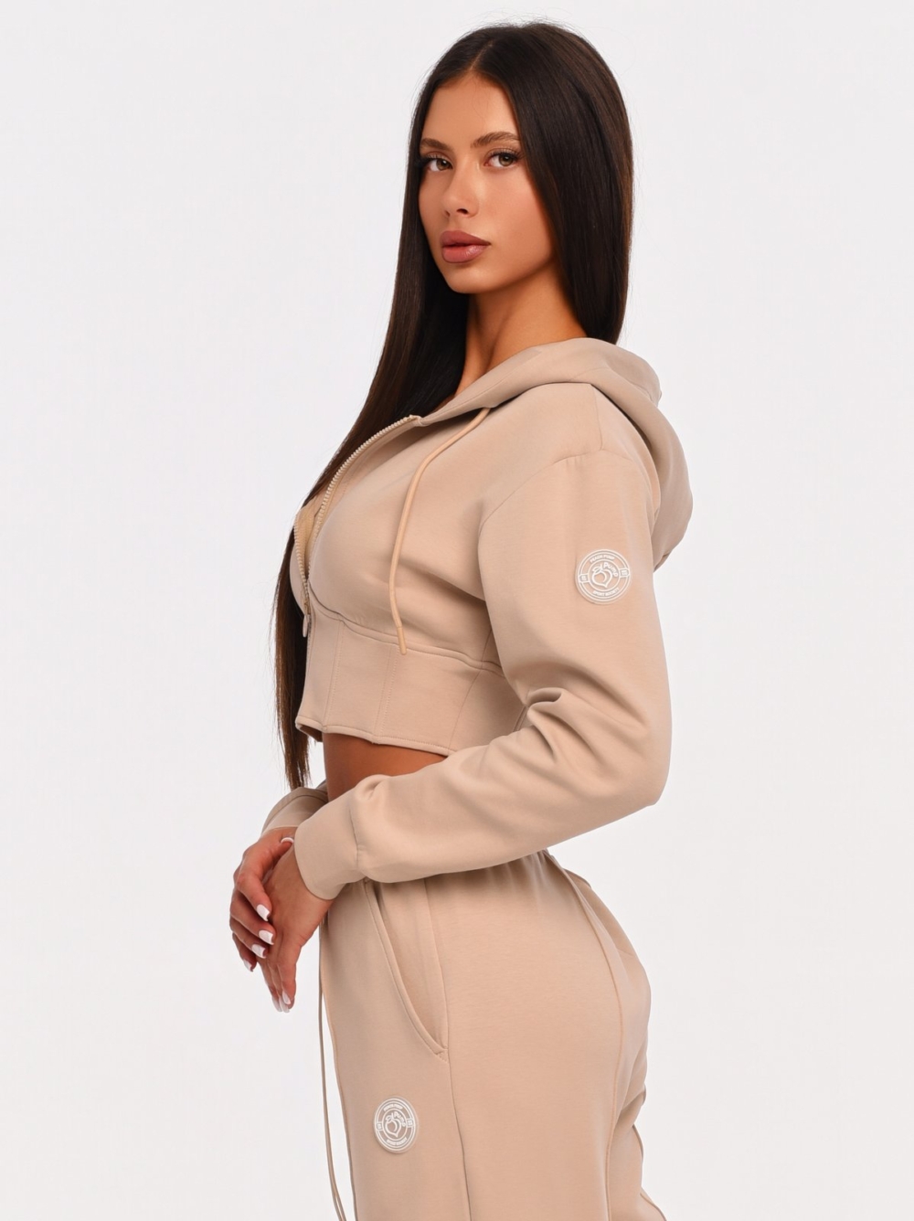 Beige cropped hoodie with rubberized Peach Pump logo on the shoulder.