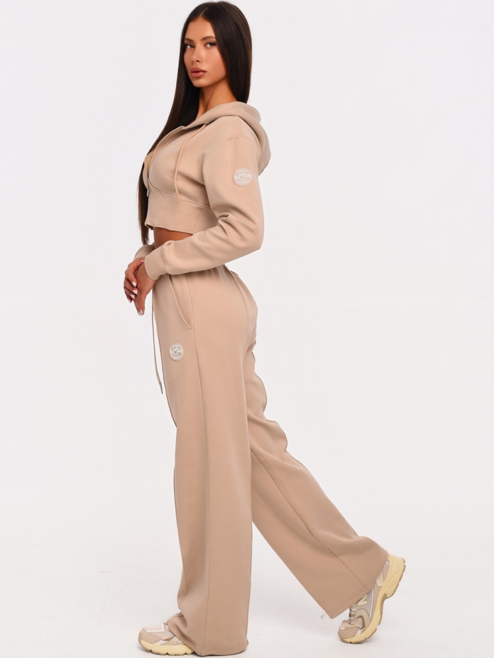 Women's beige gym set with corset-inspired cropped hoodie and wide leg joggers.