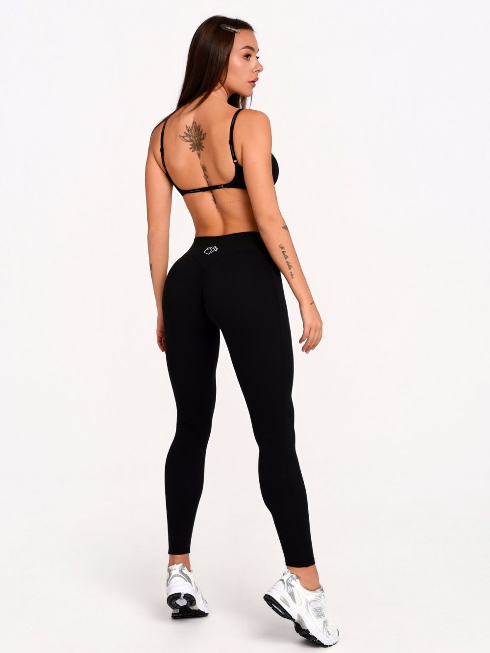 Women's full-length sports leggings in black with shaping lines around the waist and hips.